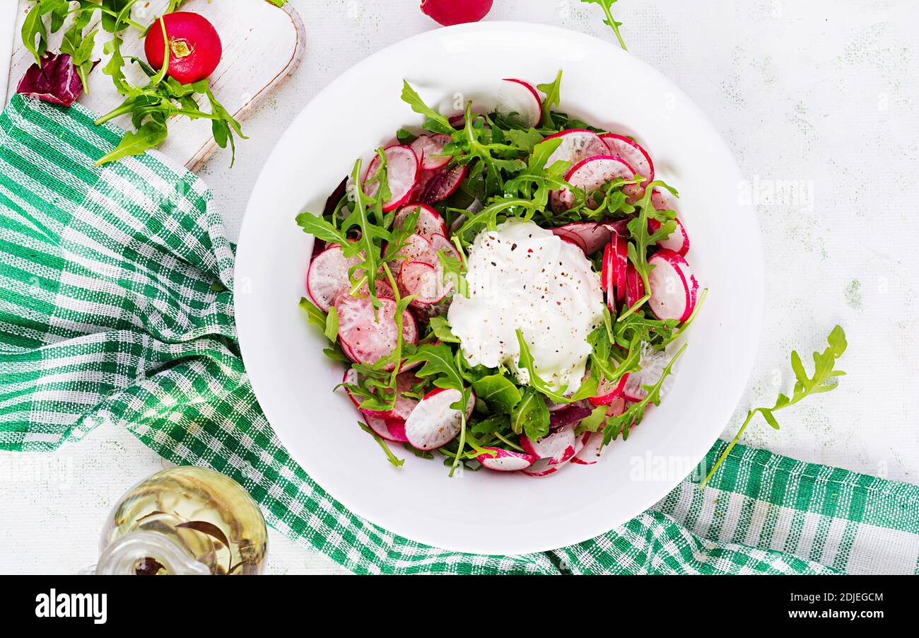 Vegetarischer Gemüsesalat aus Rettich und Rucola mit Sauerrahm. Gesundes veganes Essen. Draufsicht, Overhead, Kopierbereich Stockfoto