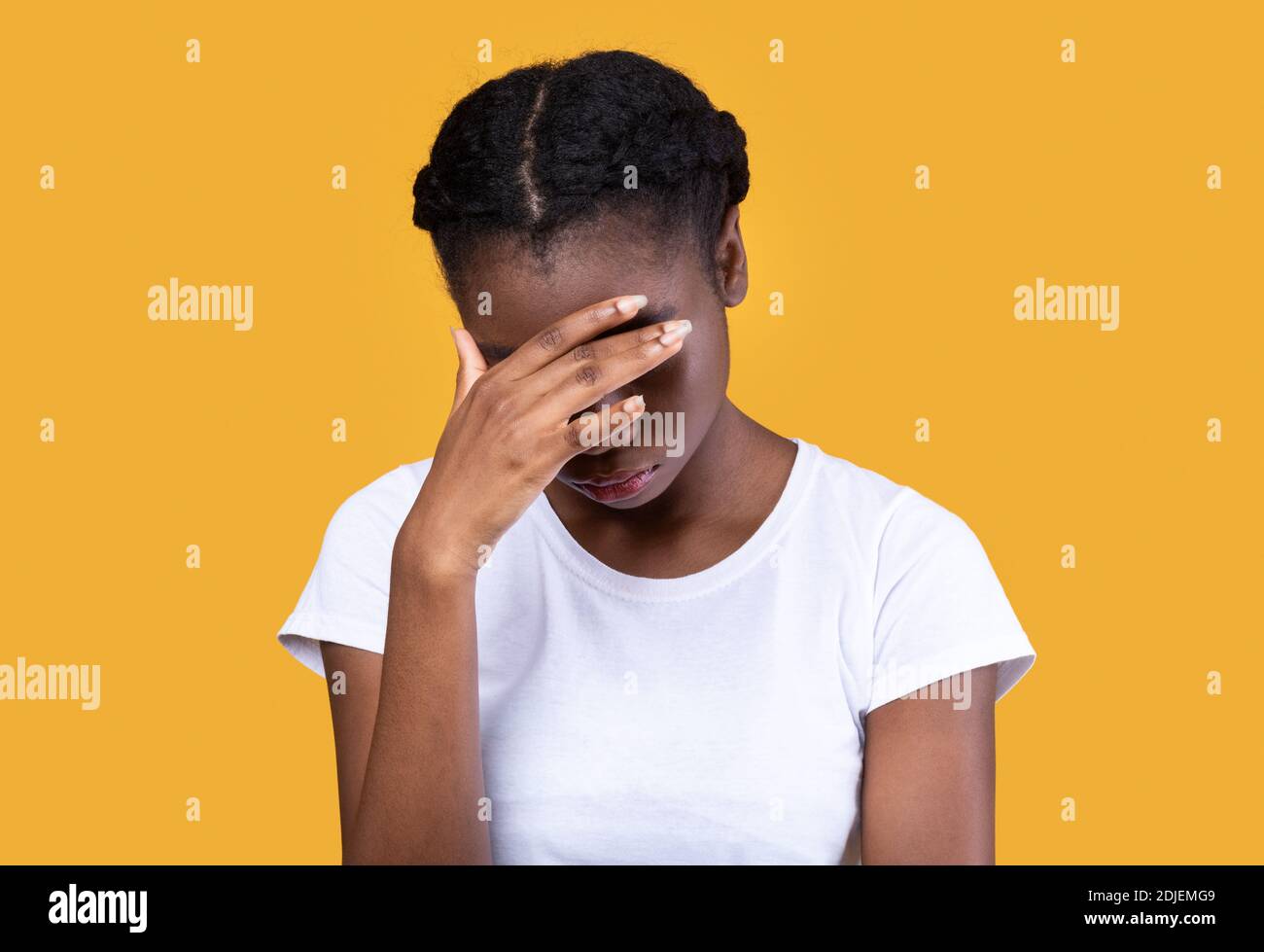 Depressive Afroamerikanische Frau, Die Gesicht Über Gelbem Studiohintergrund Bedeckt Stockfoto