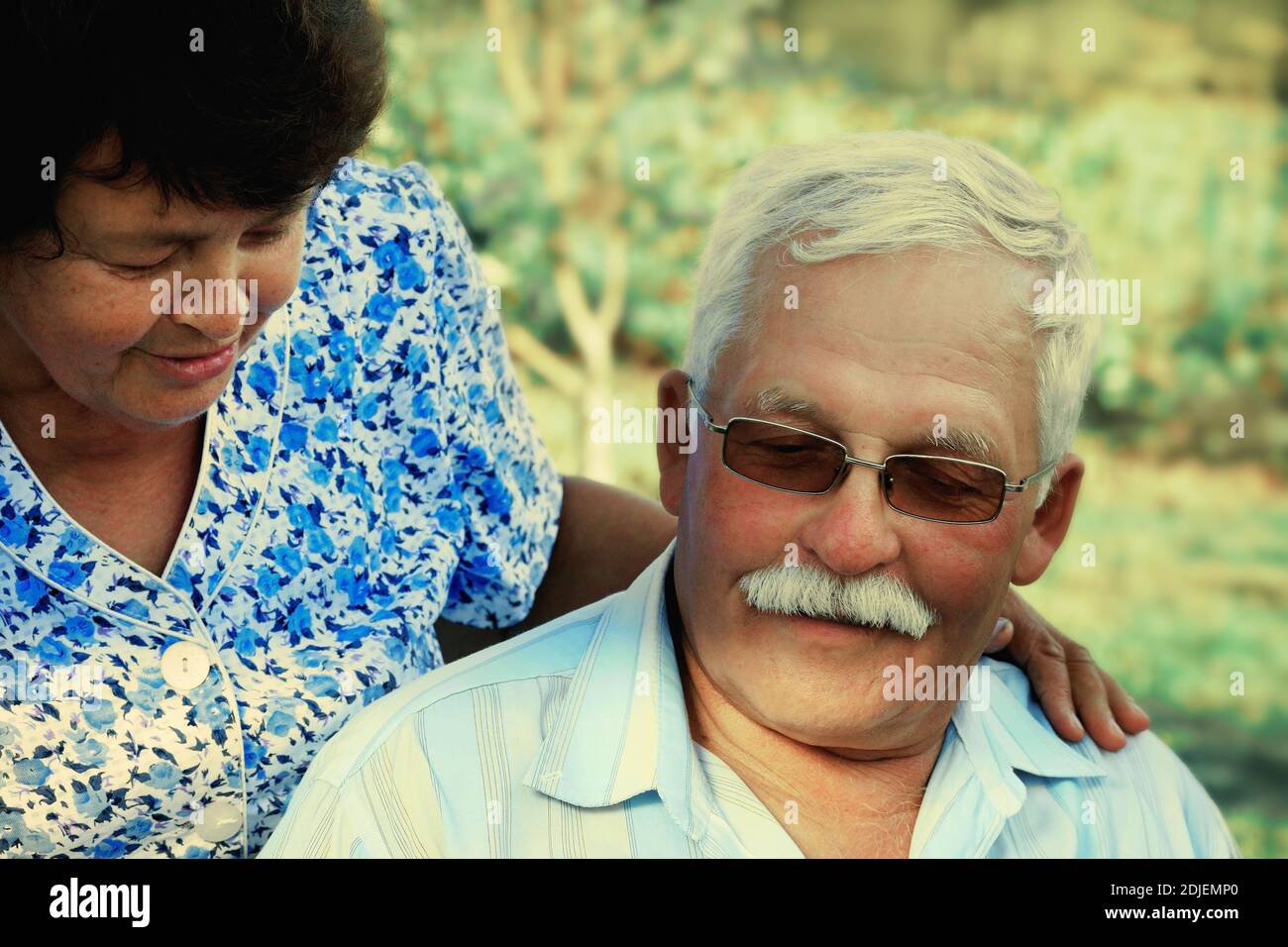 Liebevolle reife Koppel Umarmungen an einem Sommertag in der park.Senior Paar sitzen im Freien.eine ältere Frau umarmt eine alte Mann Stockfoto