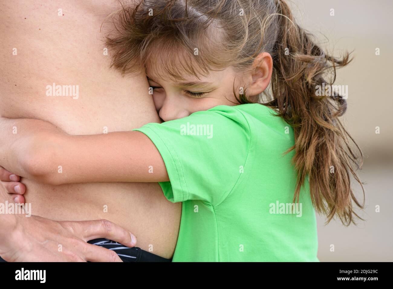 Glückliches Mädchen umarmt den Bauch eines Erwachsenen Stockfoto