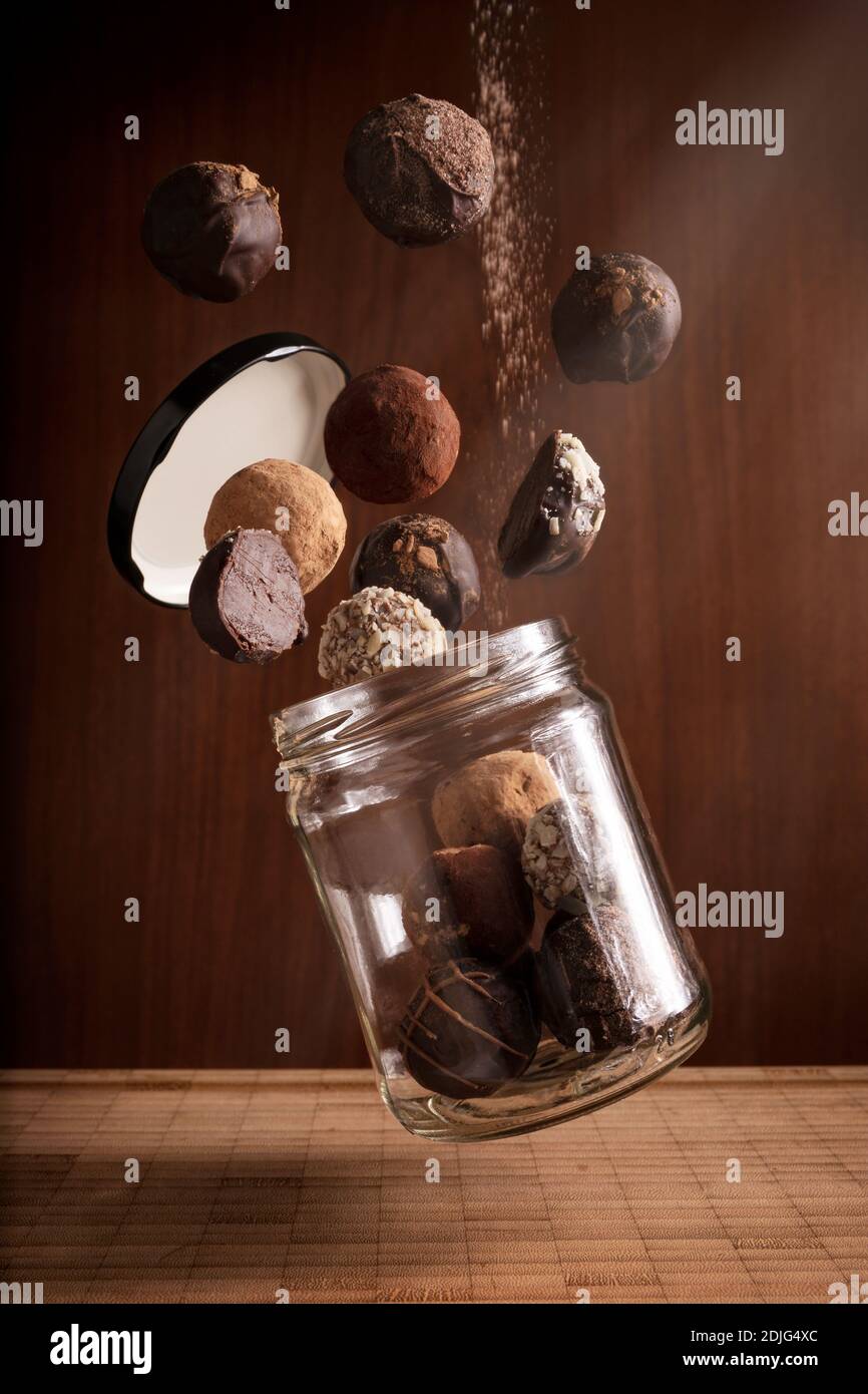 Kreative Fotografie Komposition von köstlichen fliegenden Schokolade Trüffel und schwimmende Glas auf Holzhintergrund Stockfoto