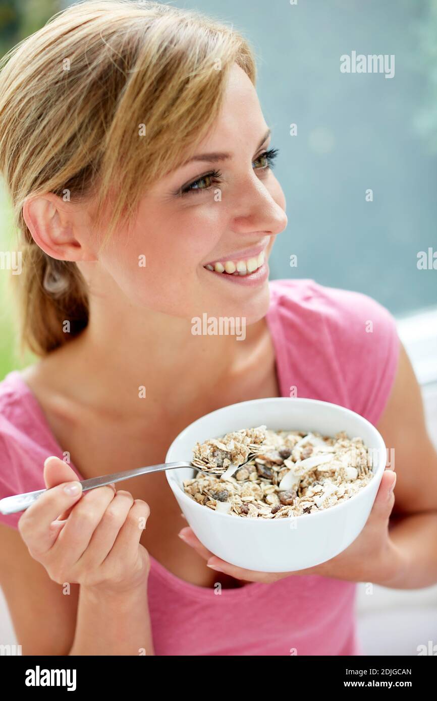 Schöne Frau, die eine Schüssel Müsli isst Stockfoto