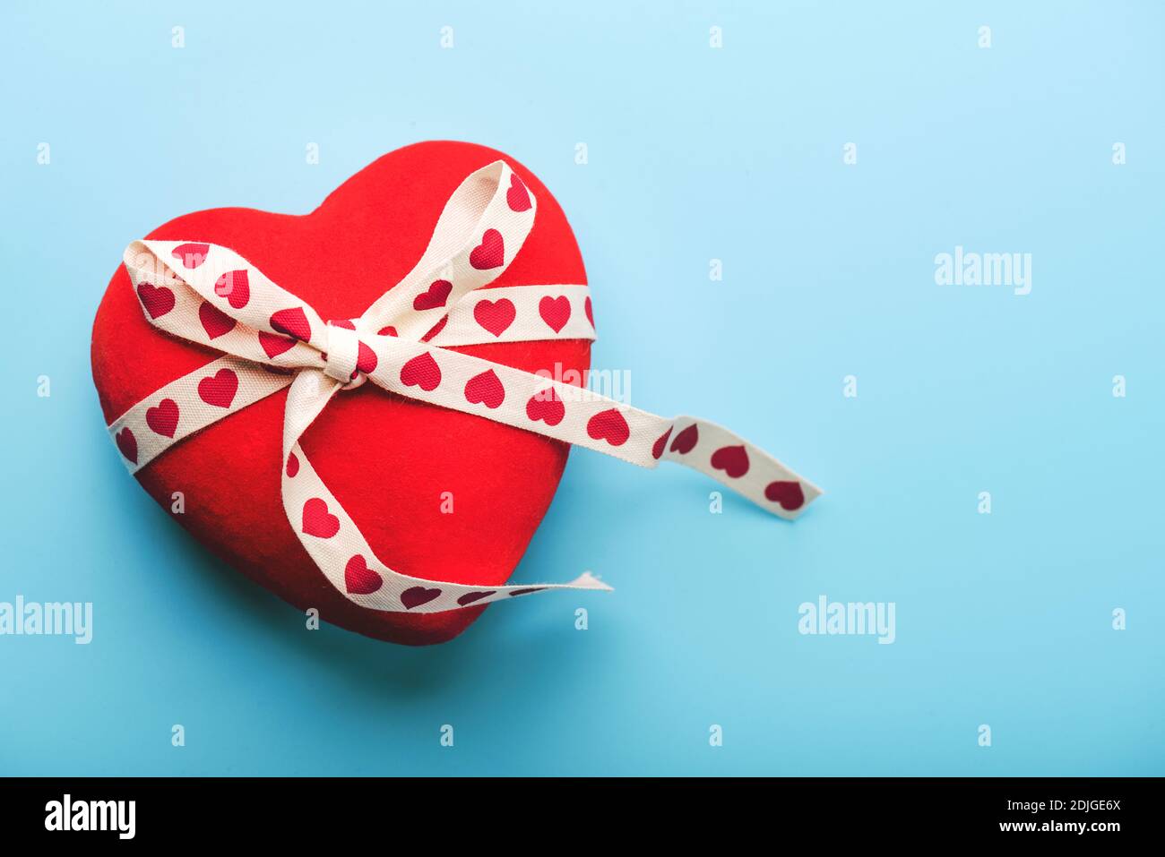 Alles Liebe zum Valentinstag.Rote Herz mit weißen Schleife mit Herzen gebunden Auf blauem Hintergrund.Valentinstag Konzept Stockfoto