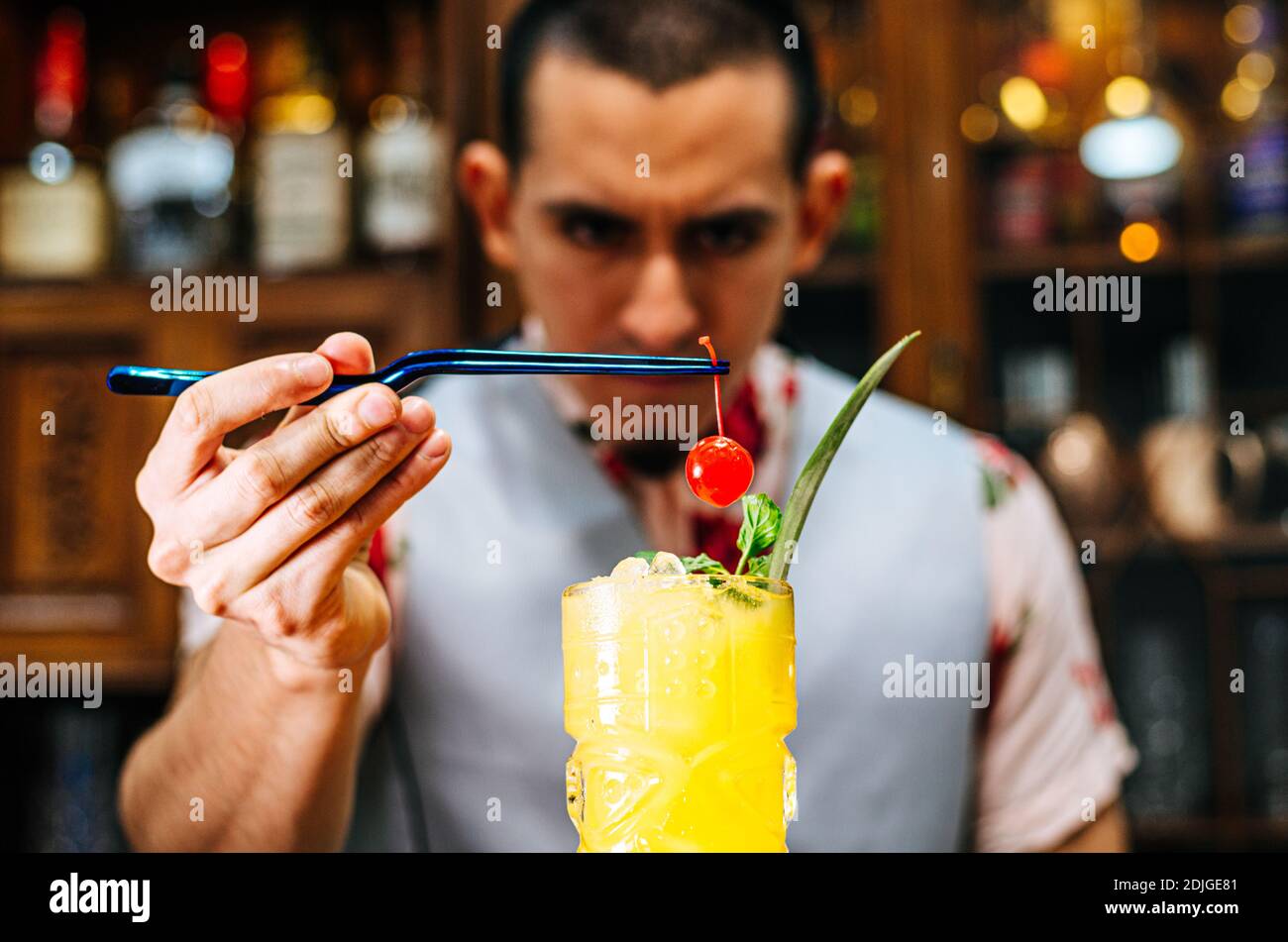 Der Barkeeper bringt eine Kirsche auf einen Tiki-Cocktail Stockfoto