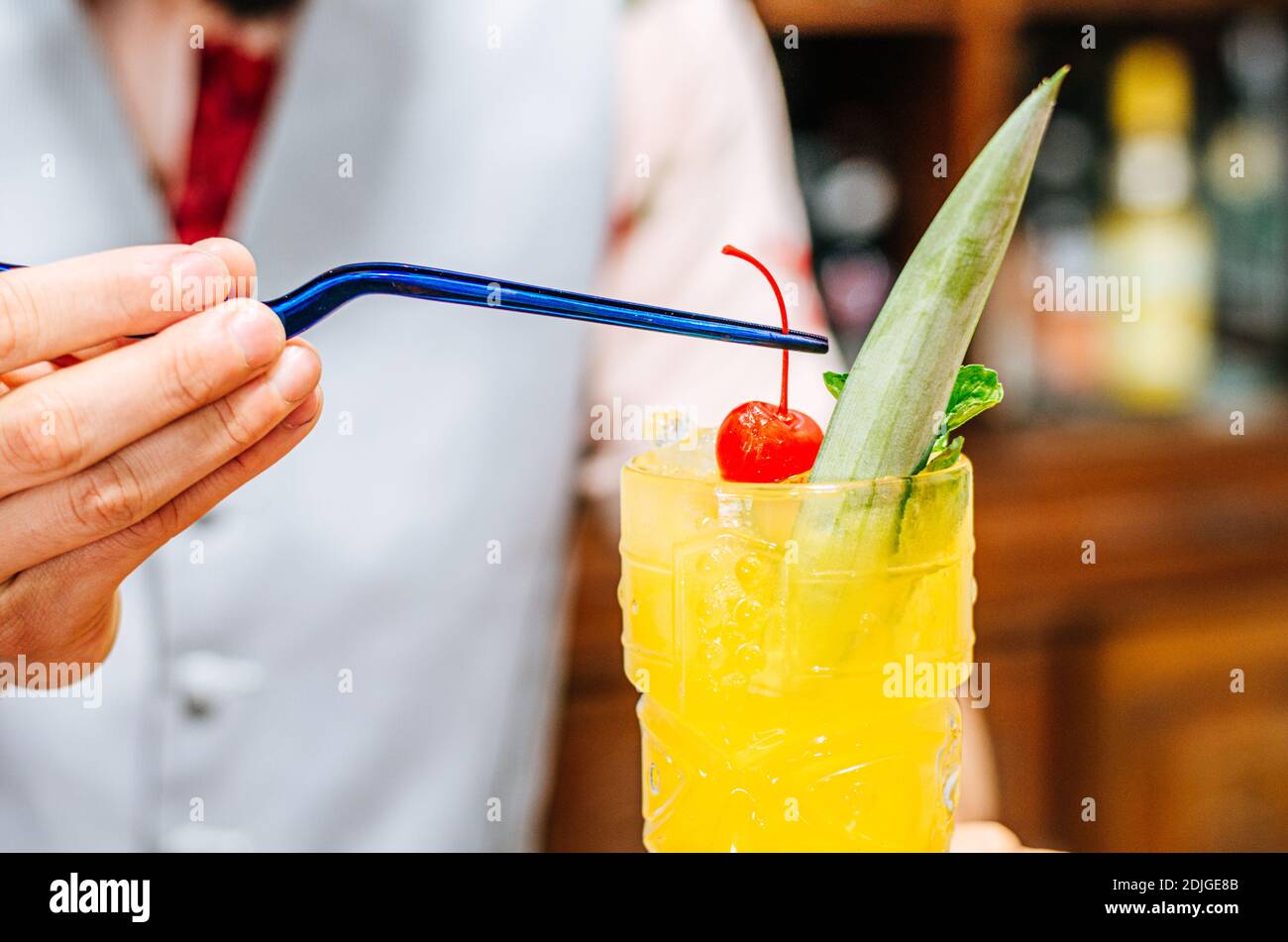 Der Barkeeper bringt eine Kirsche auf einen Tiki-Cocktail Stockfoto