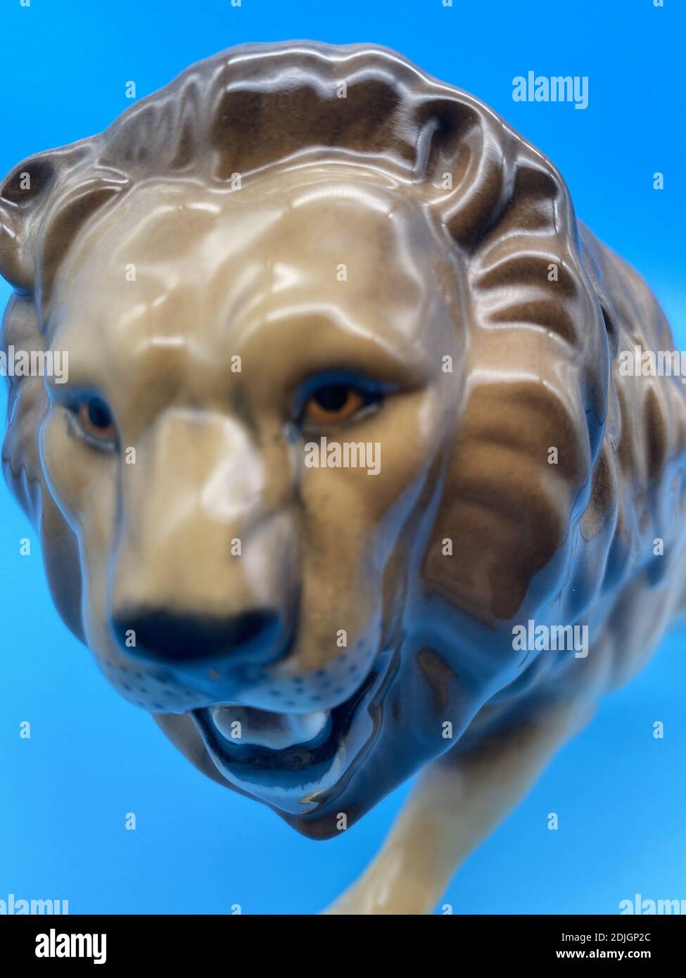Eine vertikale Nahaufnahme einer alten Porzellanfigur auf Blauer Hintergrund Stockfoto