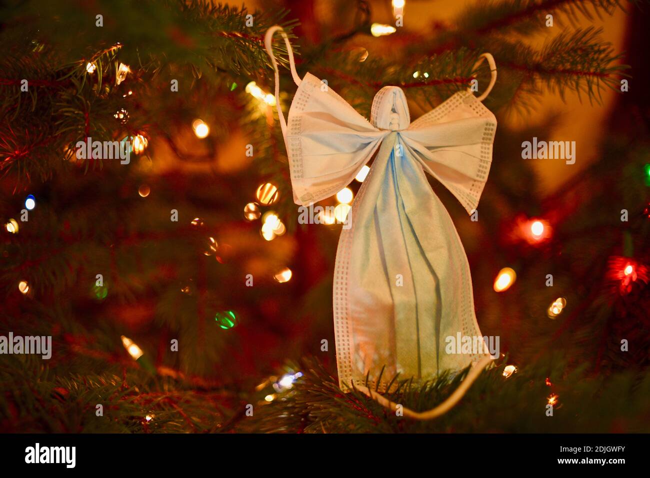 Zwei chirurgische Masken gebildet in der listigen Form eines Engels mit Flügeln, platziert auf Weihnachtsbaum, Hoffnung während covid-19 Pandemie Leiden in den USA. Stockfoto