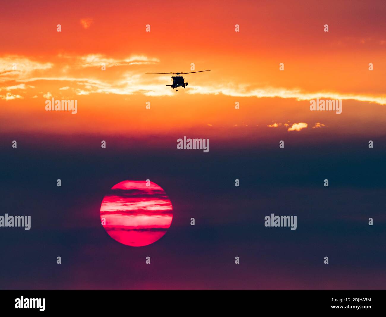Militärhubschrauber und Sonnenuntergang über der Brandung in La Jolla Shores, Kalifornien, mit Rauch von einem Feuer während Santa Ana Winden Stockfoto
