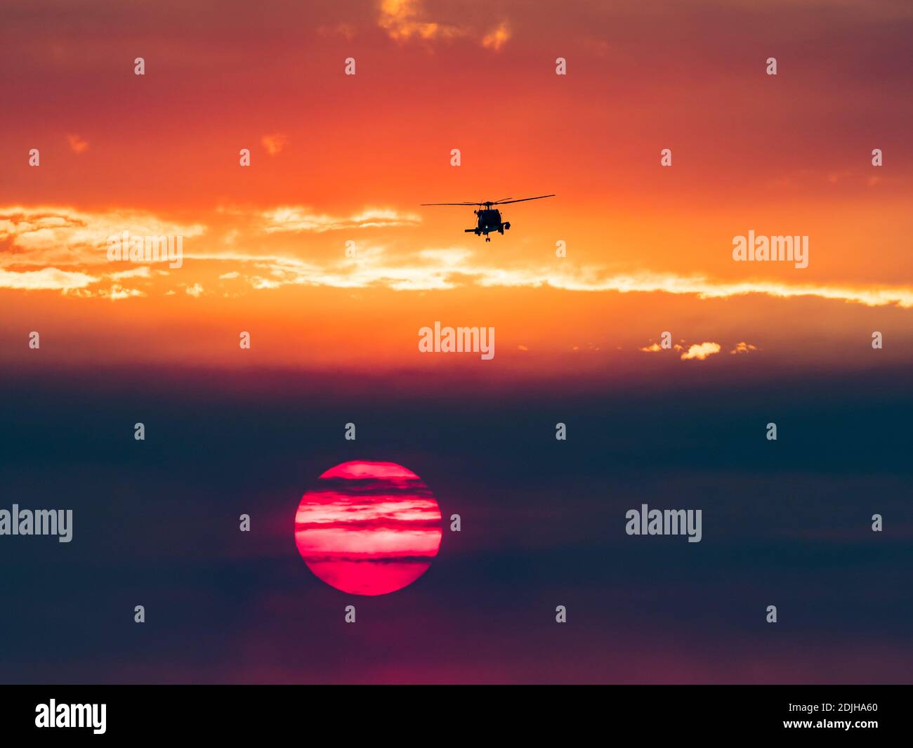 Militärhubschrauber und Sonnenuntergang über der Brandung in La Jolla Shores, Kalifornien, mit Rauch von einem Feuer während Santa Ana Winden Stockfoto