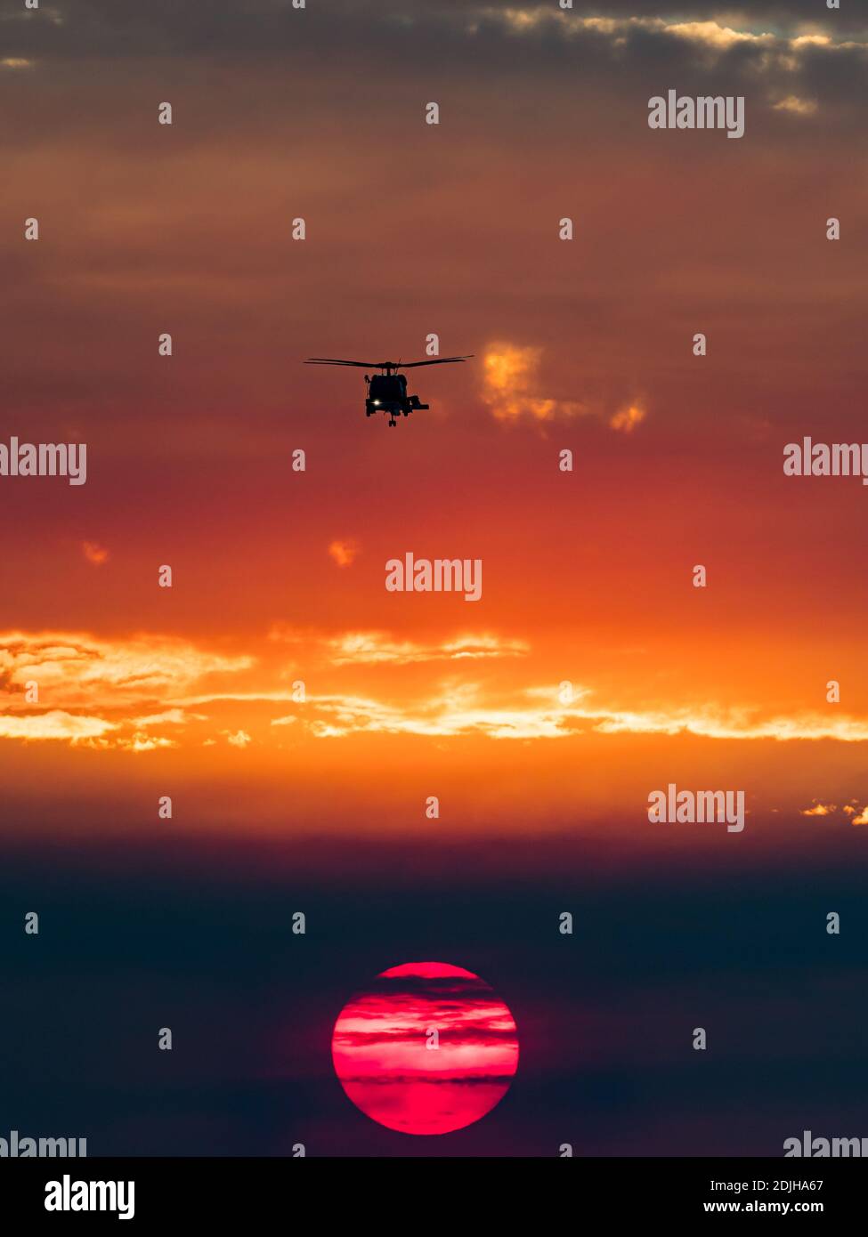 Militärhubschrauber und Sonnenuntergang über der Brandung in La Jolla Shores, Kalifornien, mit Rauch von einem Feuer während Santa Ana Winden Stockfoto