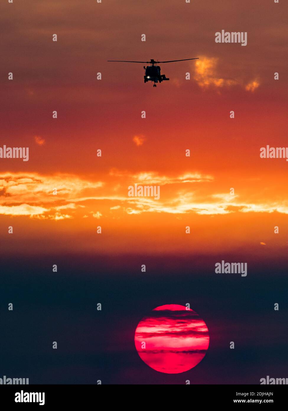 Militärhubschrauber und Sonnenuntergang über der Brandung in La Jolla Shores, Kalifornien, mit Rauch von einem Feuer während Santa Ana Winden Stockfoto
