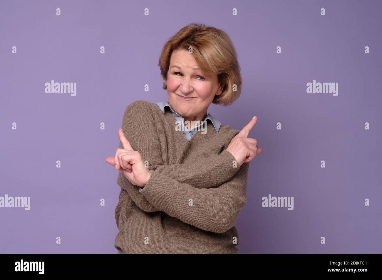 Reife Frau gefüllt mit Zögern und Zweifeln, Punkte mit Zeigefinger in verschiedenen Seiten, zeigt zwei Wege auf links und rechts, hat rätselhafte Ausdruck Stockfoto