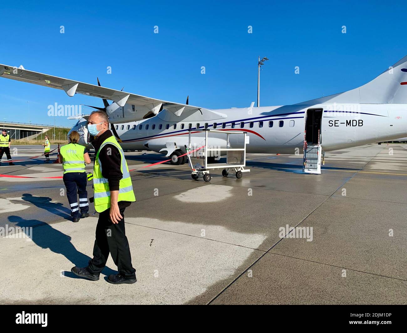 Ein Flugzeug der Lübecker Airline steht am Flughafen und wartet auf den Abflug. Bodenpersonal sichert den Zugangsbereich Stockfoto