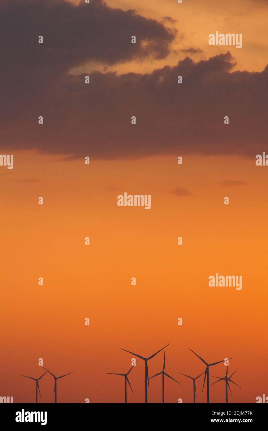 Windturbinen-Stromerzeuger Silhouetten an der Meeresküste bei Sonnenuntergang. Alternative Erzeugung erneuerbarer Energien. Stockfoto