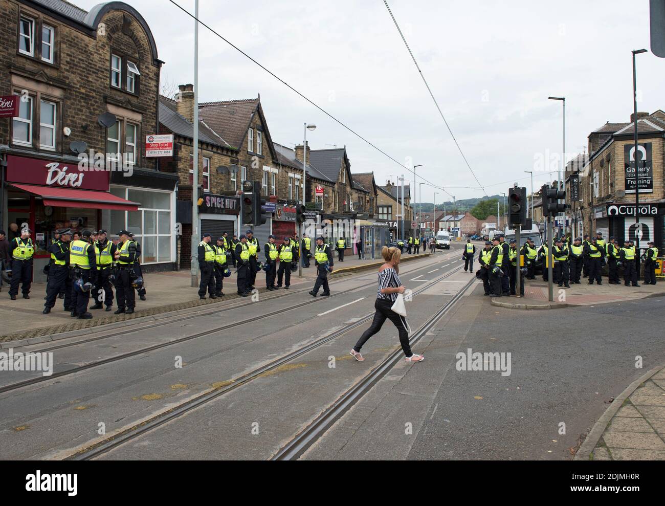 Ein Shopper geht an einer Polizeistreife in Hillsborough Sheffield vorbei Vor dem Fußballspiel zwischen Sheffield Mittwoch und Sheffield United Stockfoto