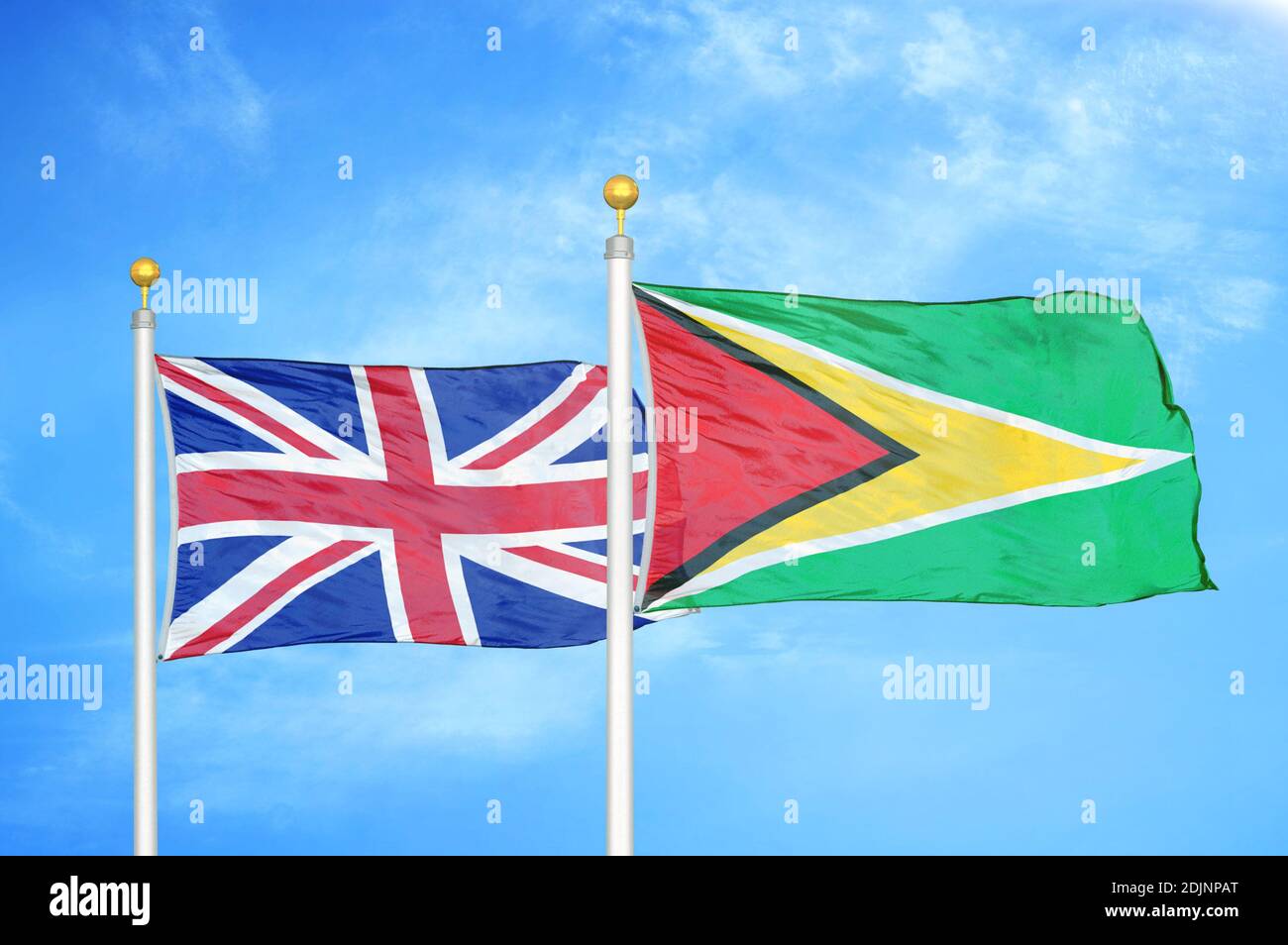 Vereinigtes Königreich und Guyana zwei Flaggen auf Fahnenmasten und blau wolkiger Himmel Stockfoto