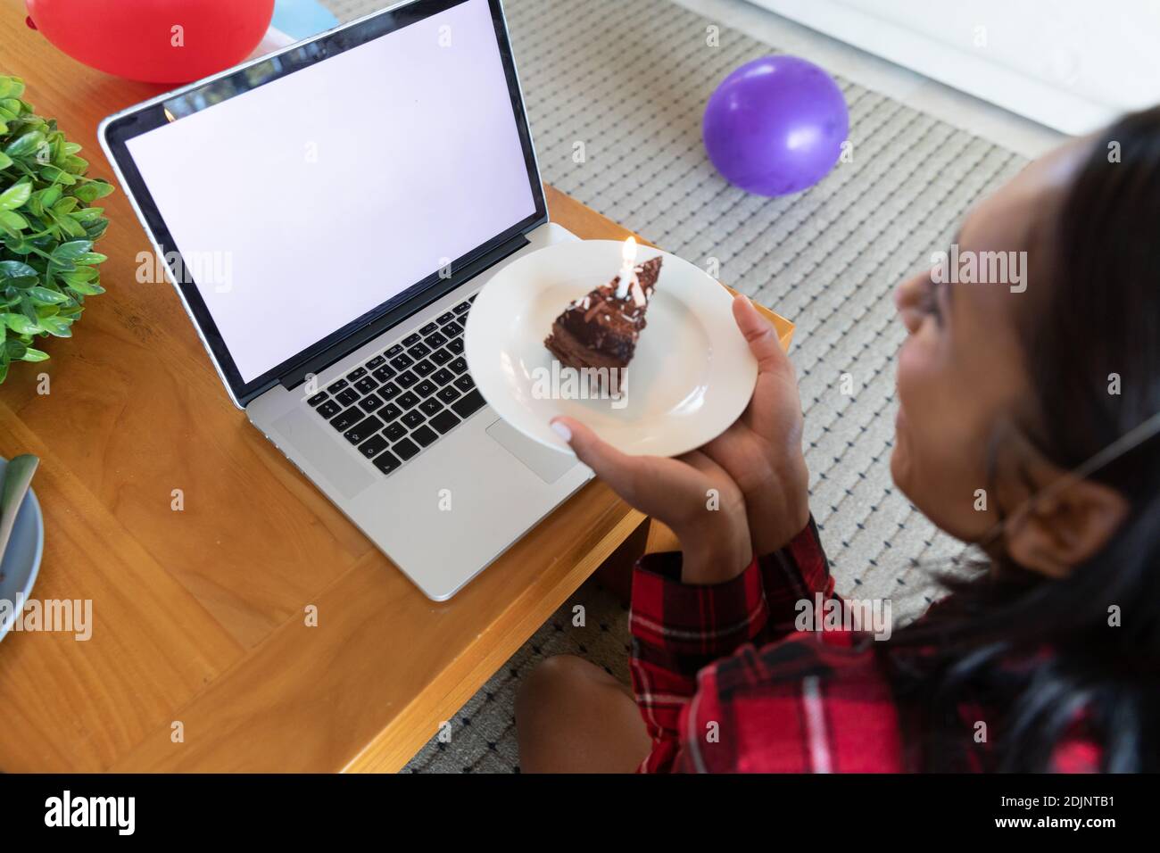 Gemischte Rennen Frau hält Geburtstagskuchen mit Laptop für Video Chatten Stockfoto