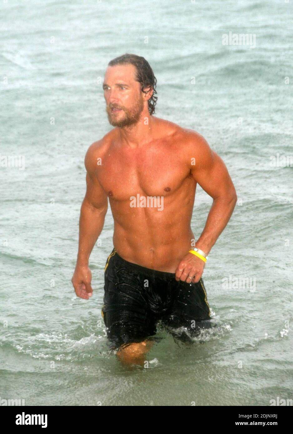 Der hunky Schauspieler Matthew McConaughey geht bei einem sintflutartigen Regenschauer ins Meer, flankiert von Fotografen, die sich unter einer Umberella versteckten, Miami Beach, FL, 8/24/06 Stockfoto