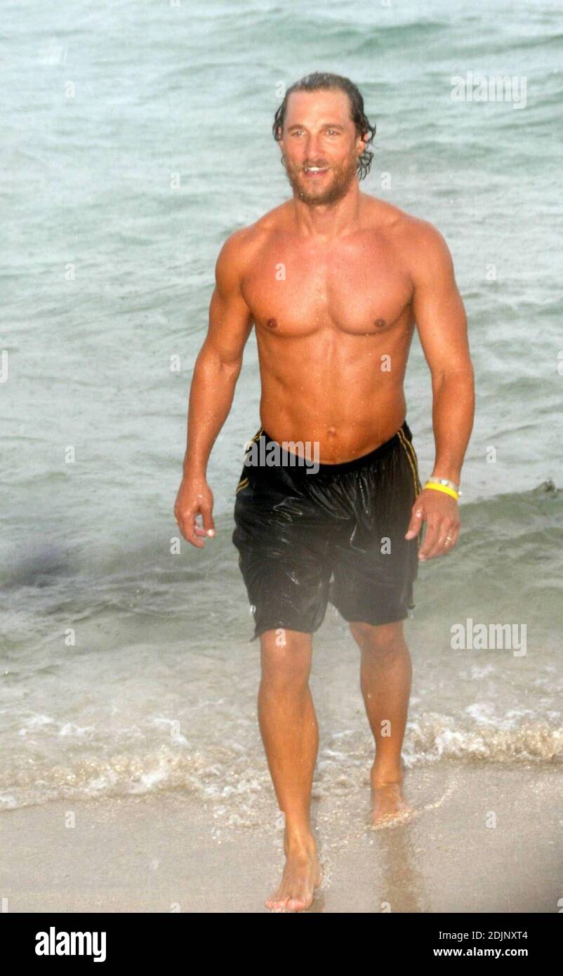 Der hunky Schauspieler Matthew McConaughey geht bei einem sintflutartigen Regenschauer ins Meer, flankiert von Fotografen, die sich unter einer Umberella versteckten, Miami Beach, FL, 8/24/06 Stockfoto