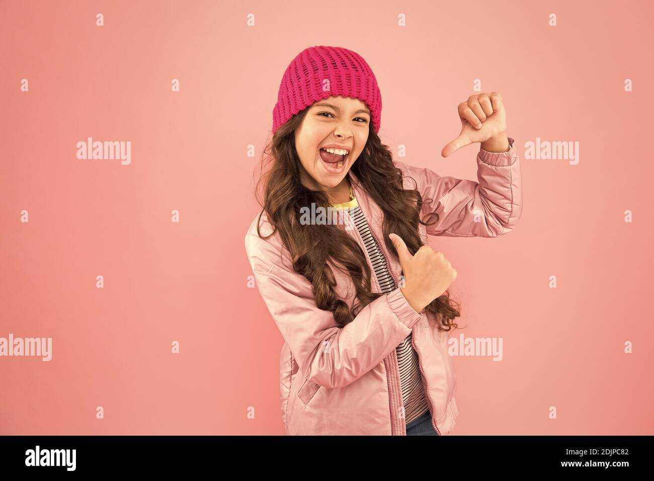 Mein Lieblingskleid. Bereit für den kalten Winter. Kaltes Klima. Fröhliches kleines Mädchen, pinkfarbener Hintergrund. Puffer-Jacke für Kinder und Strickmütze. Wintershoppen. Wie man sich im Winter warm ankleidet. Stockfoto