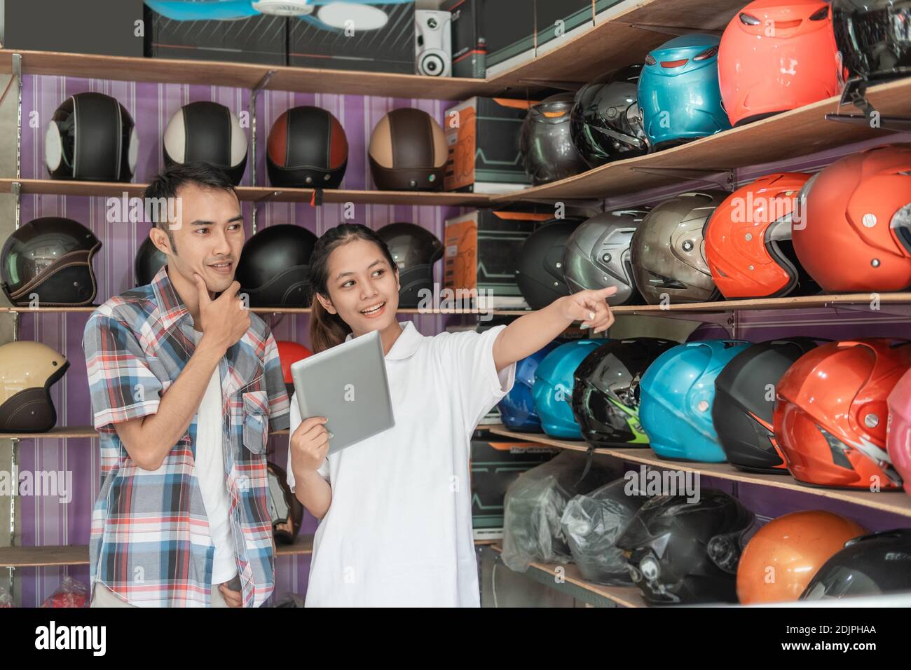Weibliche Shop-Assistenten fördern Online-Shops für Männer mit Tablets Beim Zeigen auf die Vitracken in den Helmläden Stockfoto