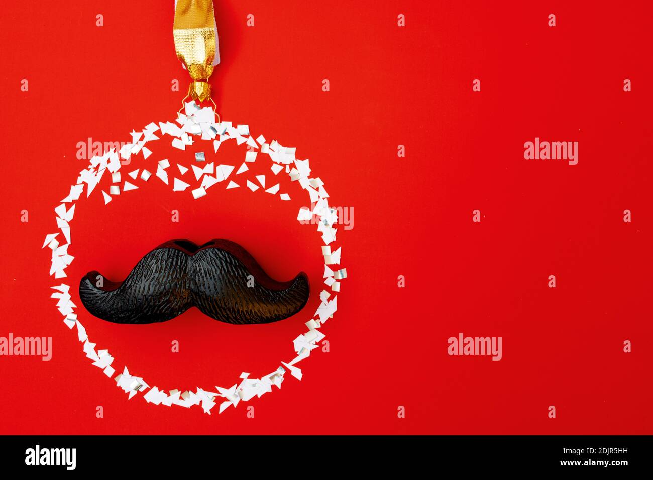 Flaches Lay mit weihnachtskugel und Schnurrbart auf rotem Hintergrund. Stockfoto