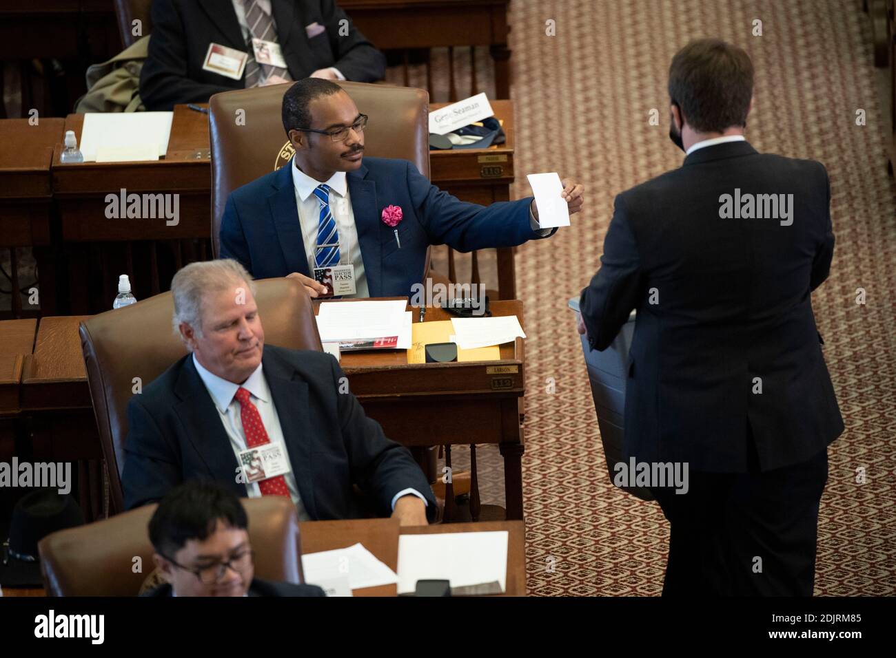 Austin, Texas, USA. Dezember 2020. Ein Helfer, der eine Maske trägt, sammelt Stimmzettel, während die Wähler des texanischen Präsidenten am Montagnachmittag in der Repräsentantenkammer die Stimmzettel für Präsident Donald Trump auswarfen. Wie erwartet gingen alle 38 Texas-Stimmen an Präs. Trump und Vice Präs. Mike Pence. Kredit: Bob Daemmrich/Alamy Live Nachrichten Stockfoto