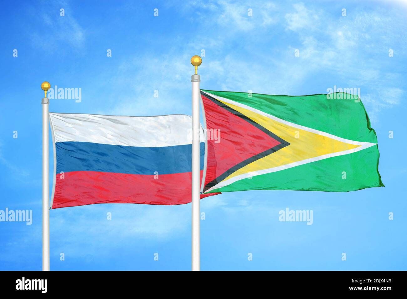 Russland und Guyana zwei Flaggen auf Fahnenmasten und blau bewölkt Himmel Stockfoto