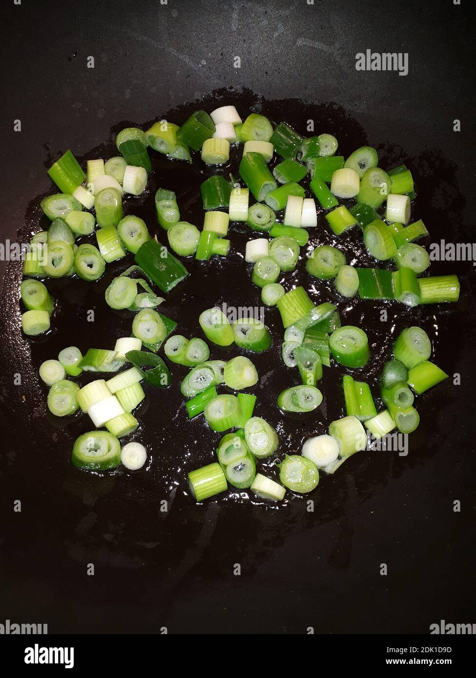 Ein Blick von oben auf die frisch geschnittenen grünen Zwiebeln Gekocht in einem Wok mit Öl gefüllt Stockfoto