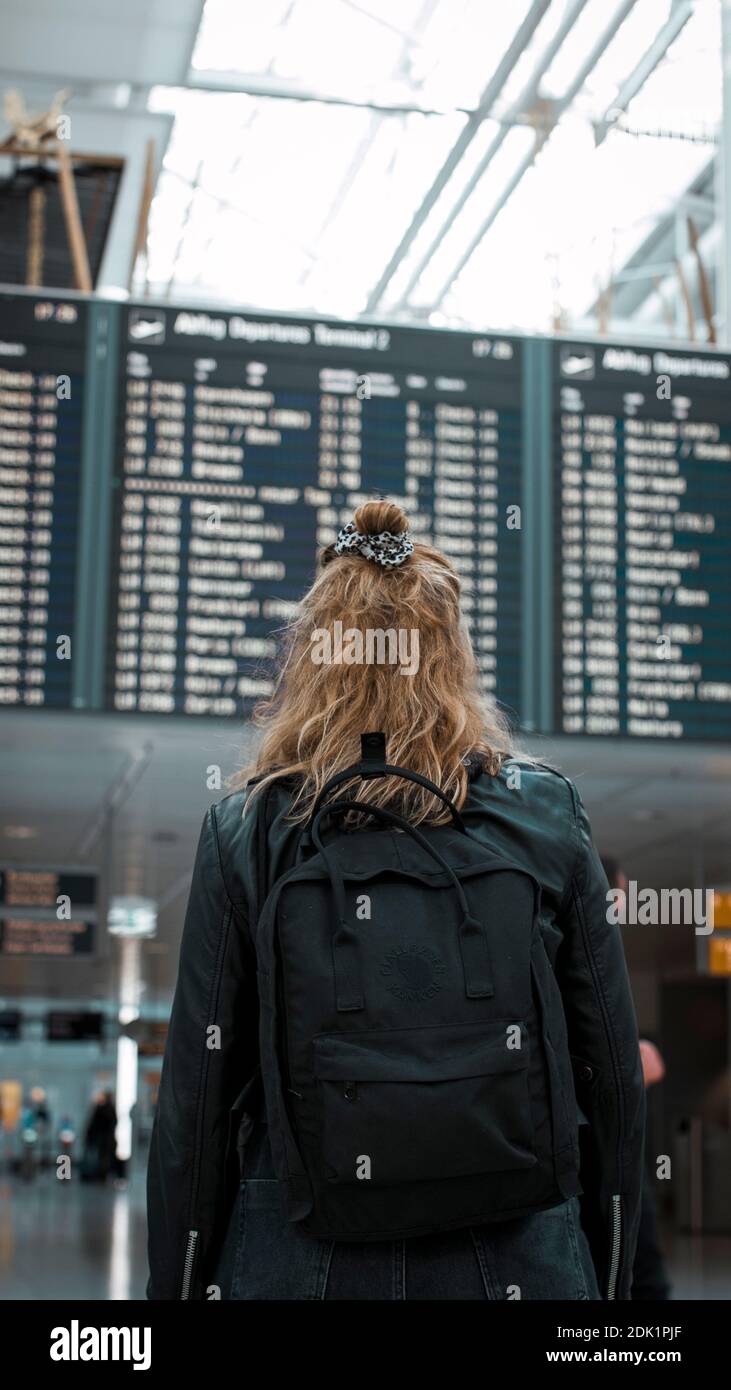 Junge blonde Frau am Flughafen München mit Mund-Nasen-Maske / Corona-Reise / Fluggast mit Schutzmaske Stockfoto