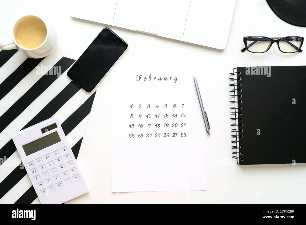 Kalender Februar auf weißem Desktop flach Ley mit einer Tasse Kaffee und einem Notebook. Stockfoto