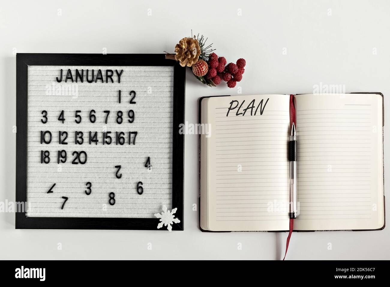 Notizblock für Notizen zu Zielen und Plänen für das neue Jahr, Kalender und Weihnachtsbaumschmuck auf dem Desktop. Inschrift in englischer Ebene. Stockfoto