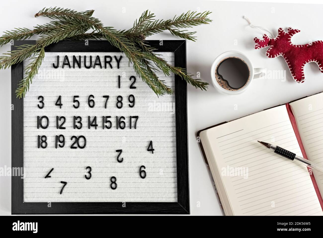 Notizblock für Notizen von Zielen und Plänen für das neue Jahr, Kalender, eine Tasse Kaffee, Weihnachtsbaumschmuck auf dem Desktop Stockfoto