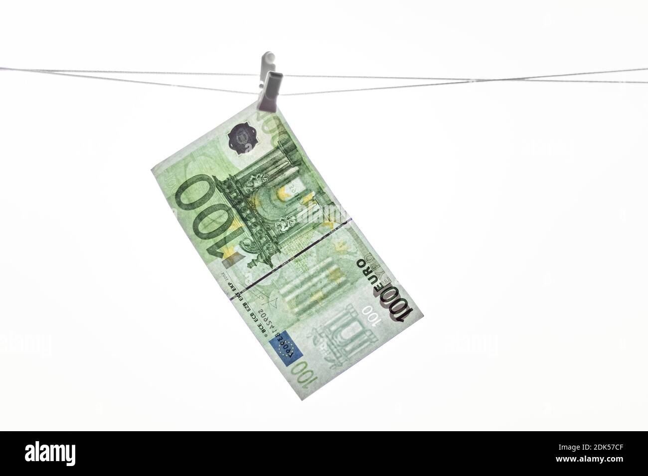 Eine Euro-Banknote aus Papier hängt an einem Seil mit einer Wäscheklammer auf dem Hintergrund des Fensters. Stockfoto