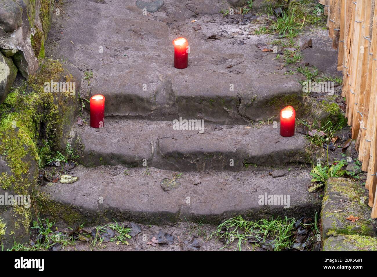 13. Dezember 2020, Sachsen-Anhalt, Langenstein: Vor dem Eingang einer Höhlenwohnung brennen drei rote Kerzen. In Langenstein im Harz wartet man förmlich darauf, dass eine Hobbit-Pfeife um die Ecke kommt. In der Kleinstadt bei Halberstadt gibt es noch ein Dutzend gut erhaltene Höhlenwohnungen, die an die Aue der beiden Bestseller "der Herr der Ringe" und "der Hobbit" des Schriftstellers J.R.R. erinnern Tolkien. Die Behausungen wurden von Bauernfamilien ab 1855 mit Hammer und Meißel in mehrere Sandsteinfelsen gehauen. Heute kümmert sich ein Verein Stockfoto