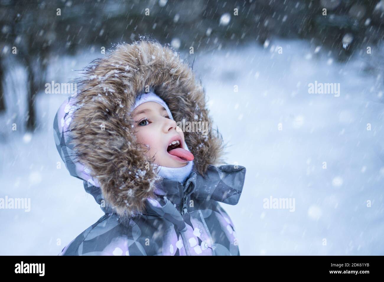 Porträt eines niedlichen kleinen Mädchen, das Schneeflocken Mund im Winter Tag fängt. Stockfoto