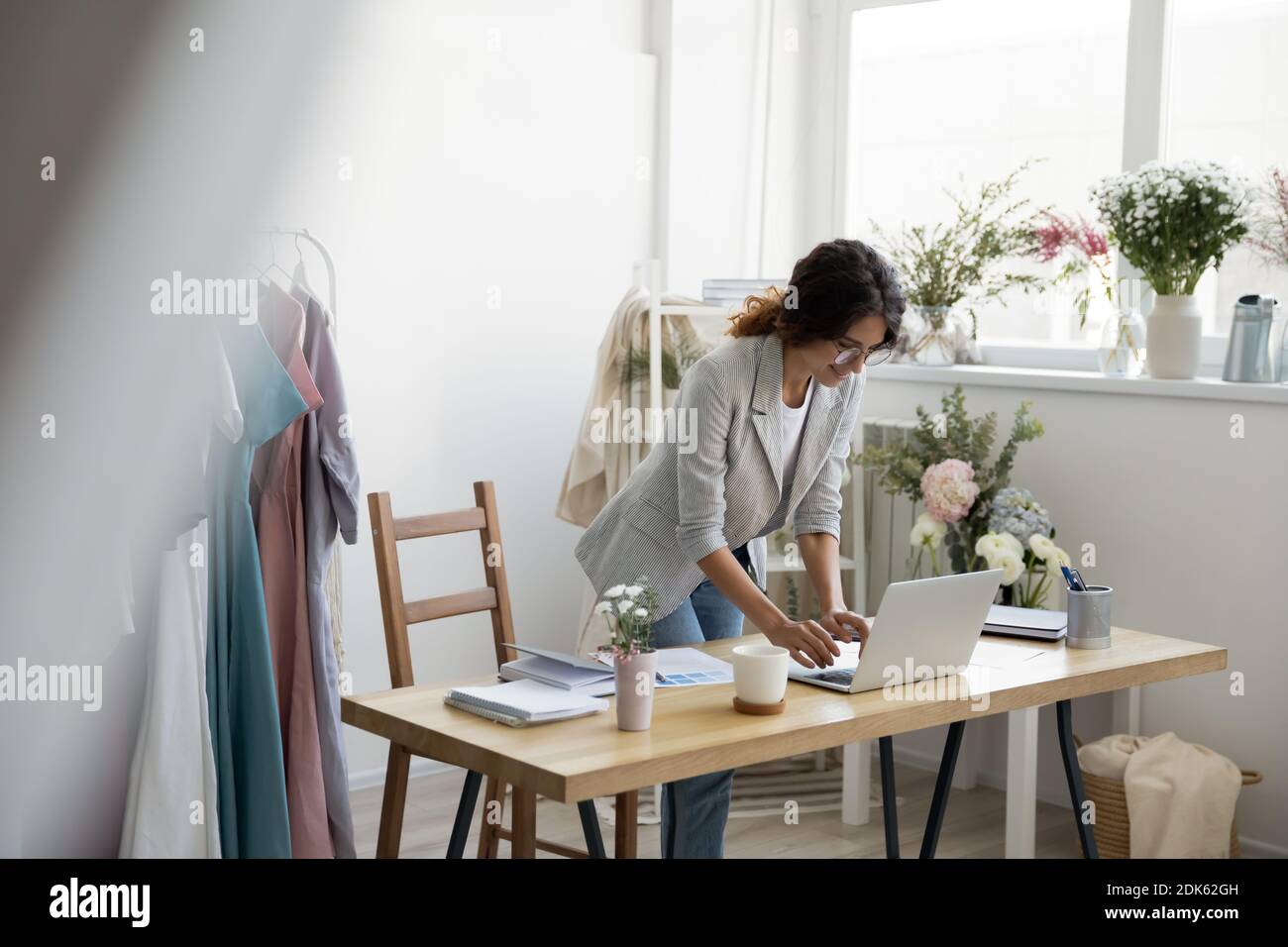 Motivierte junge weibliche Kleidung Designerin steht am Laptop Druck E-Mail Stockfoto