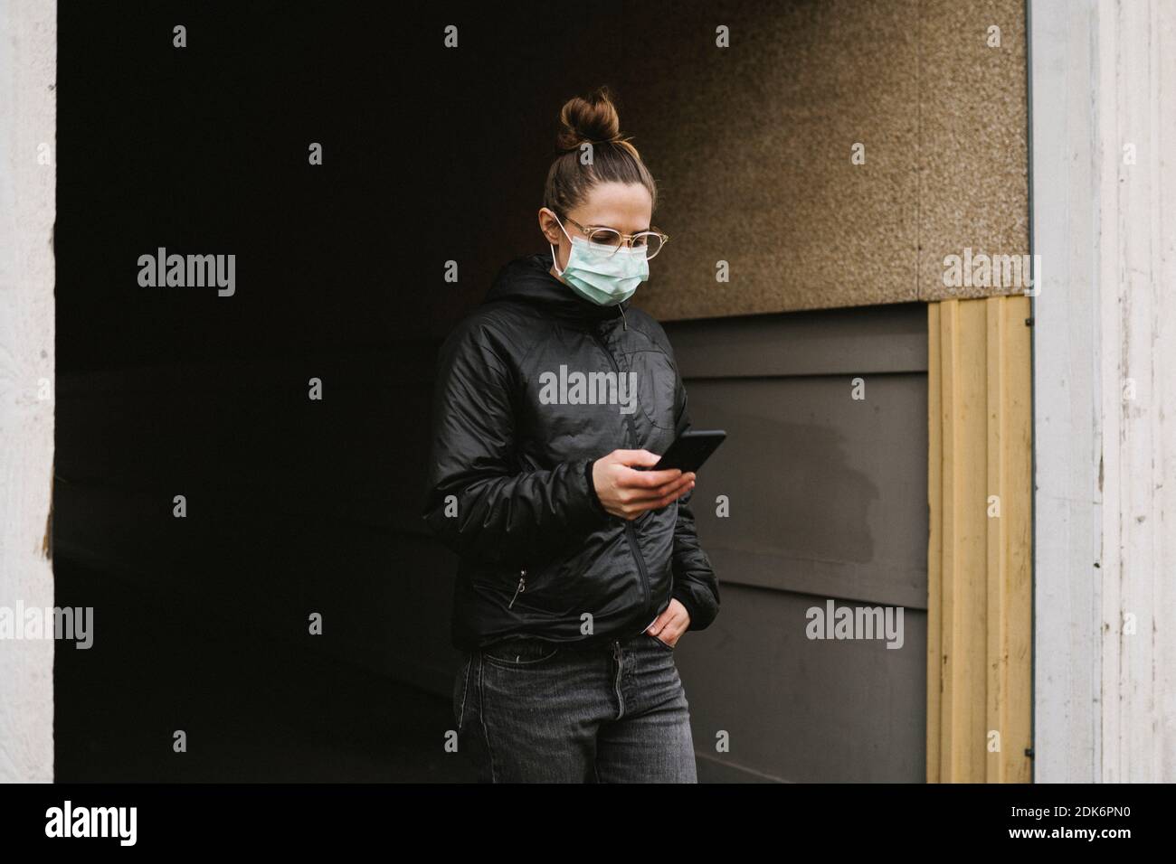 Frau trägt Gesichtsmaske mit Handy Stockfoto
