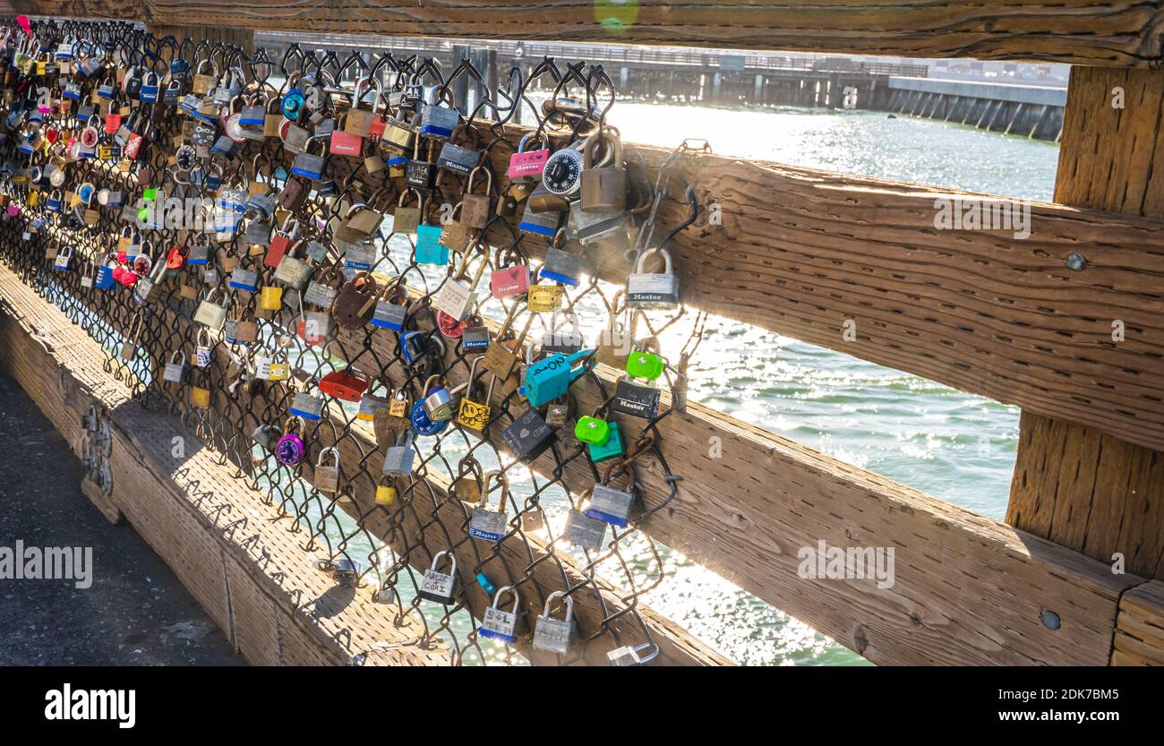 Liebesschlösser, die von Paaren an einem Zaun aufgehängt wurden, um ihre ewige Liebe am Pier 39 zu markieren. Stockfoto