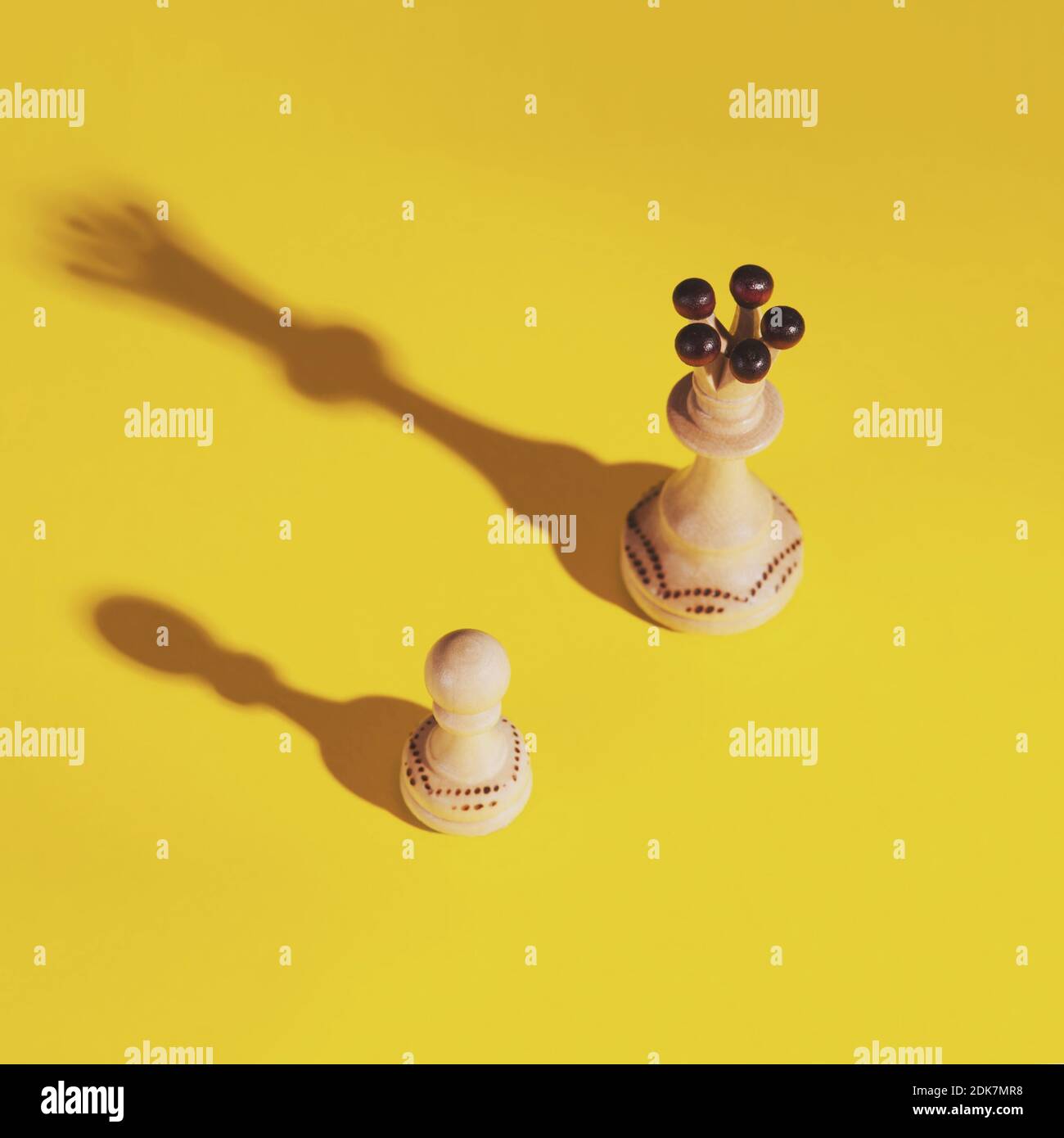 Creative background with wooden chess pawn and queen with shadow on the yellow background. Selective focus. Stockfoto