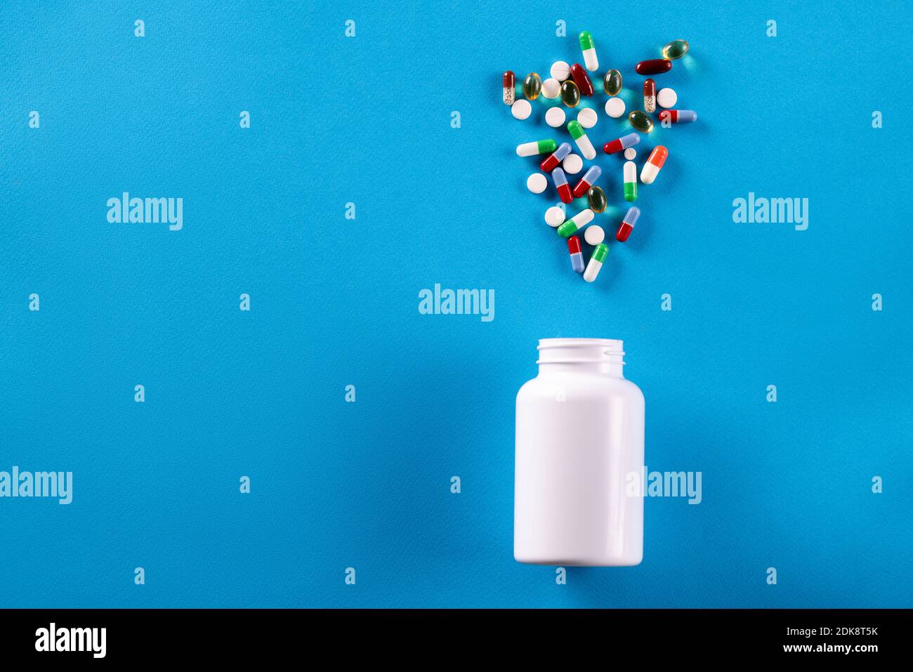 Weißes Glas mit verstreuten Pillen. Unkontrollierter Drogenkonsum Stockfoto