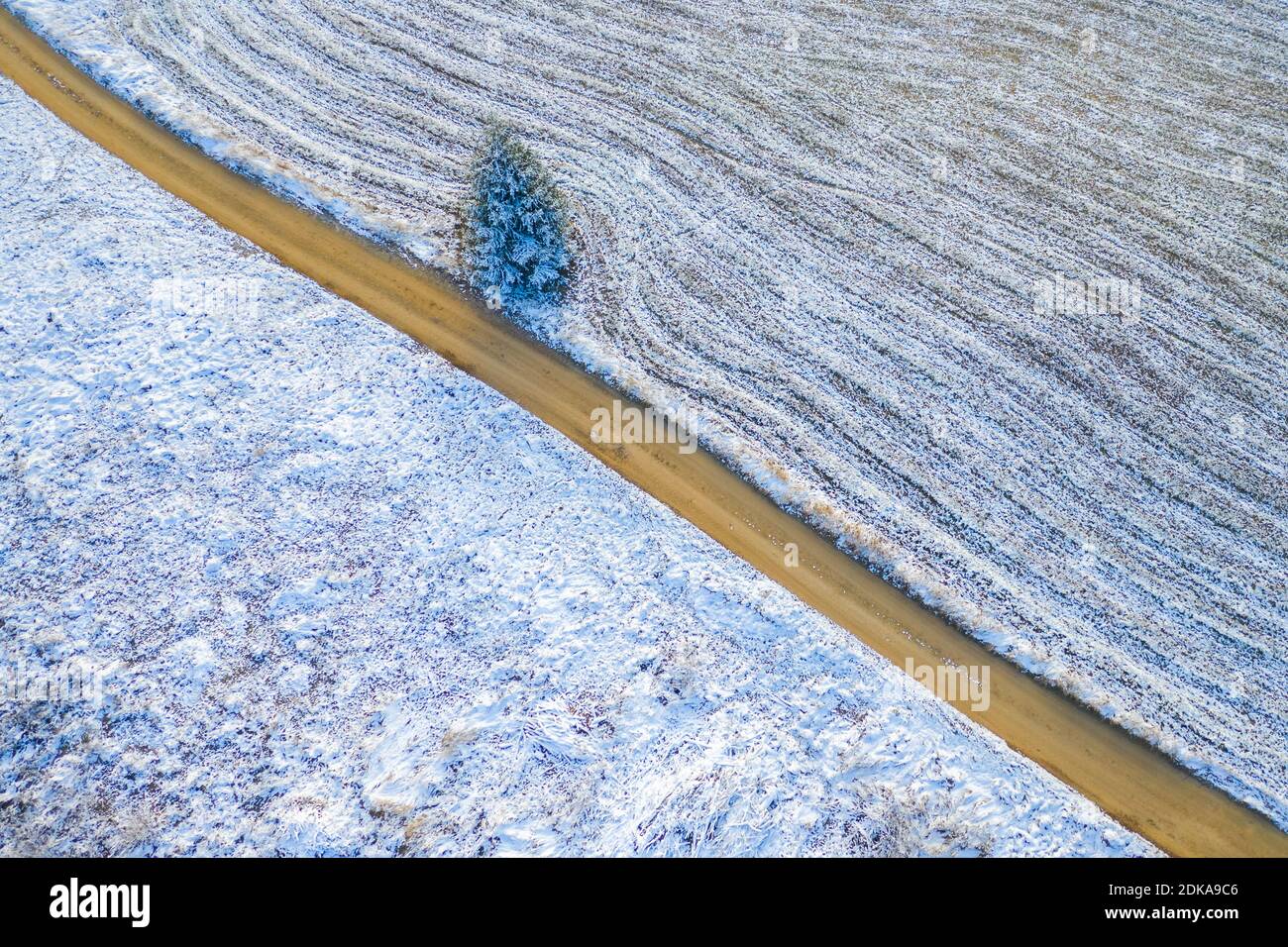 Windige Winterstraße in schneebedeckten Feldern, von oben nach unten Luftaufnahme. Stockfoto