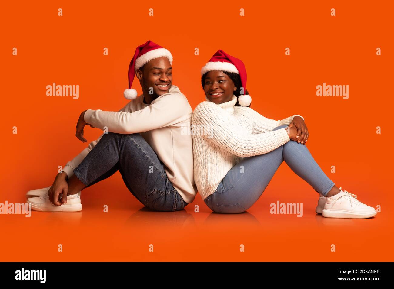 Romantisches Schwarzes Paar In Santa Hüte Sitzen Und Drehen An Einander Stockfoto