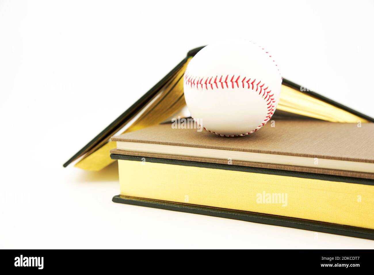 Gelehrter Athlet und Integration von Akademikern und Sport gesehen in Konzeptionelle Stillleben von Büchern und Baseball auf weißem Hintergrund Stockfoto