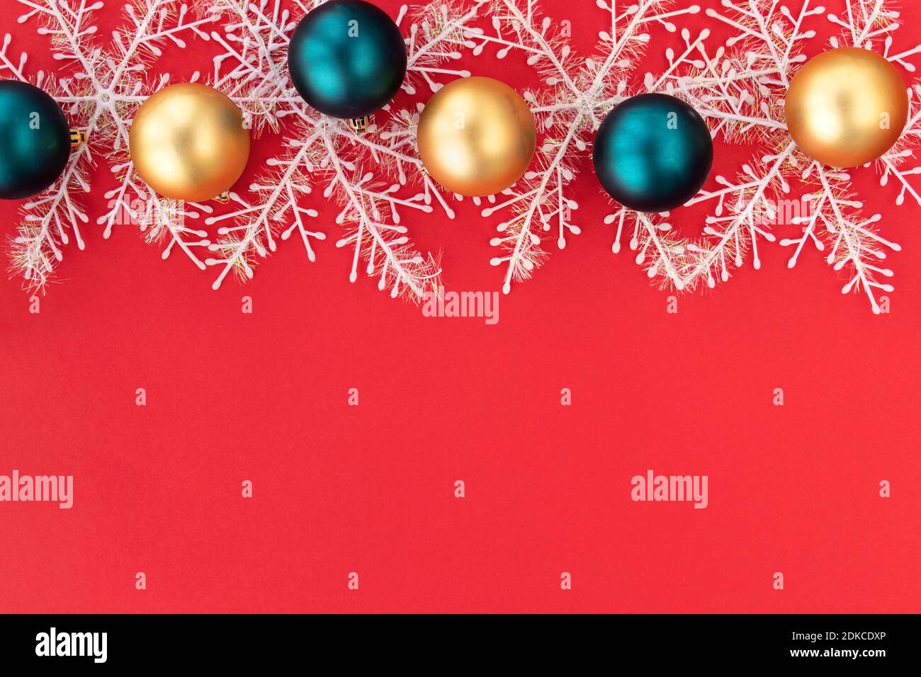 Bunte Weihnachtskugeln und Schneeflocken. Goldene und blaue Weihnachtskugeln auf rotem Hintergrund mit Platz für Text. Weihnachten und Weihnachten Konzept.Copy Raum. Draufsicht. Flach liegend Stockfoto