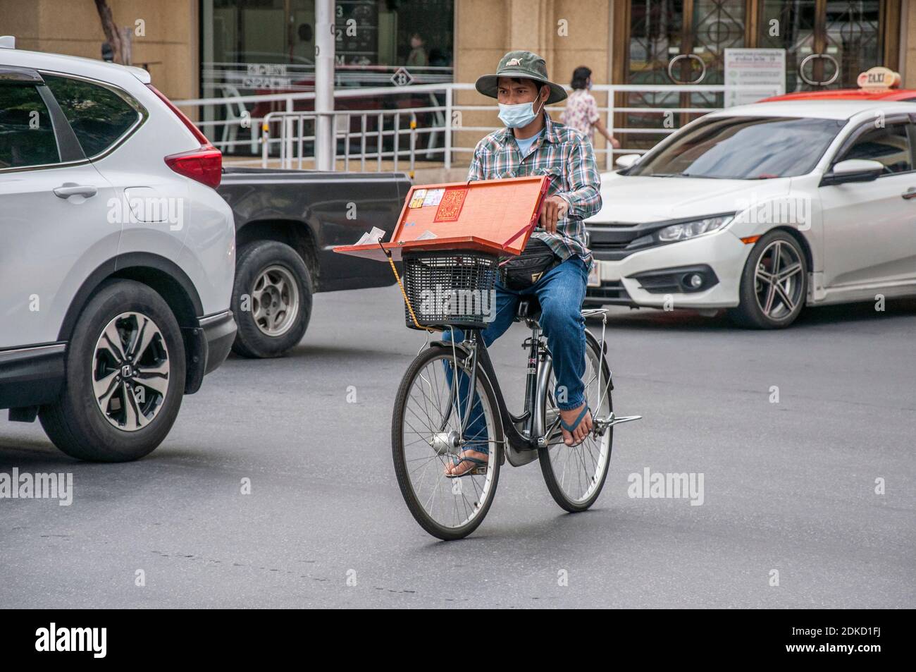 Ein Lotterieverkäufer sah eine Gesichtsmaske beim Ridding sein Fahrrad in Bangkok.Menschen tragen Schutzmasken als Luftschadstoff PM2.5 steigt zu ungesunden Ebenen in Bangkok. Stockfoto