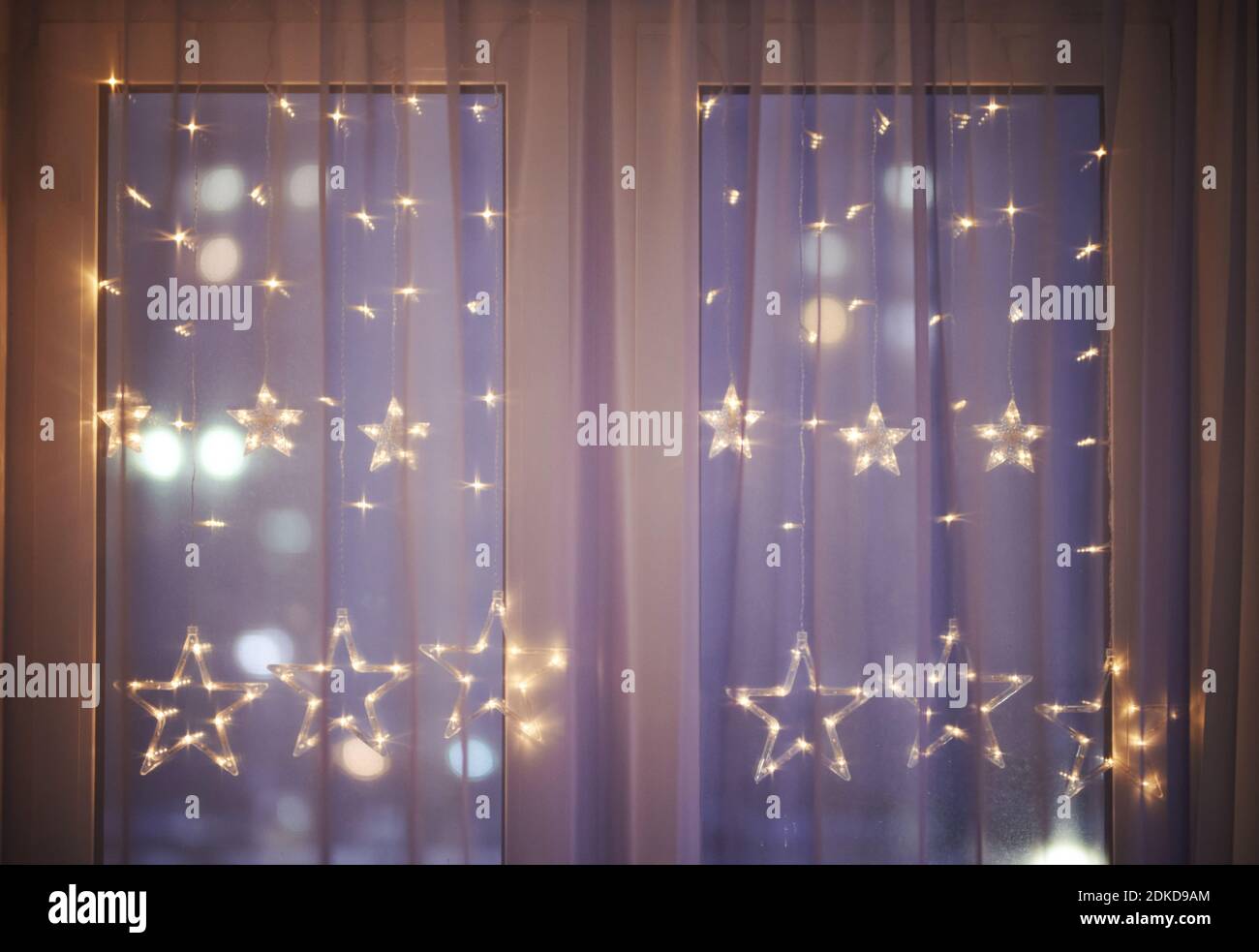 Weihnachten Dekoration Lichter unter Fenstervorhang auf unscharfen Straßenhintergrund Stockfoto
