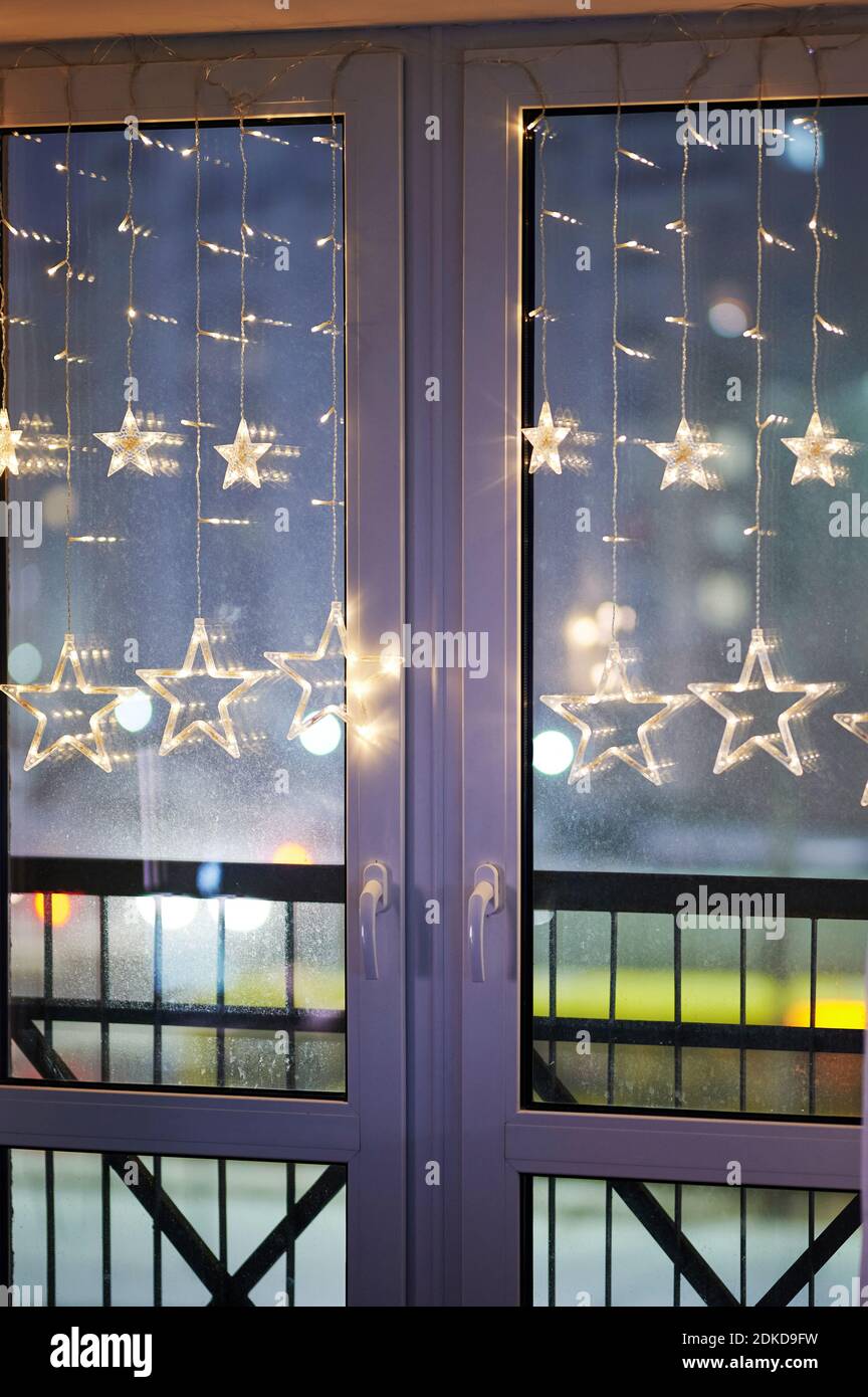 Beleuchtetes Fenster mit weihnachtlichem Licht auf unscharfer Straße Stockfoto