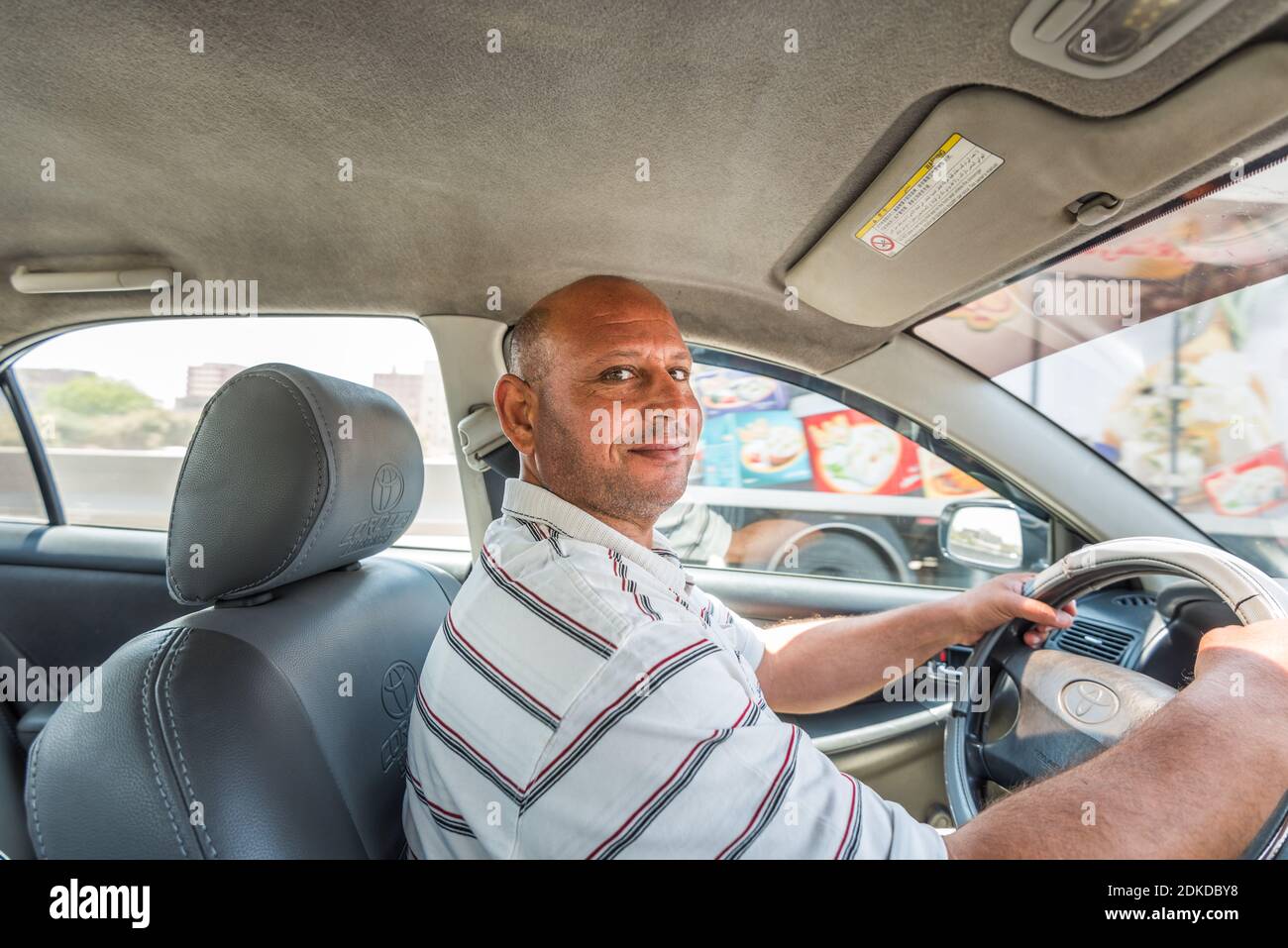 Ein männlicher Fahrer aus dem mittleren Alter, der ein Auto in einem fährt Straße Stockfoto