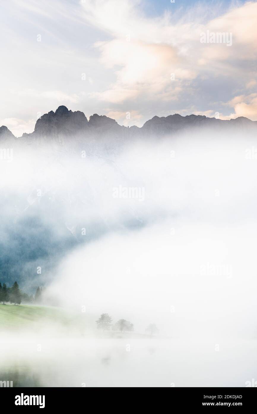 Herbststimmung an einem kleinen See in den bayerischen Alpen, im Hintergrund das Karwendelgebirge, eine kleine Halbinsel im Nebel und die Spiegelung im Wasser. Die neblige Atmosphäre mit den zerklüfteten Bergen hat eine fast mystische Wirkung. Stockfoto